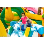Happy little girl having lots of fun on a jumping castle during sliding.