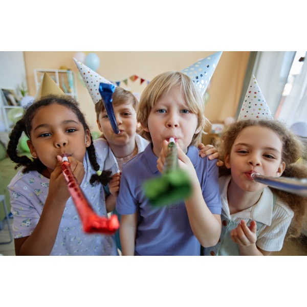 Three children holding party blowers and having fun