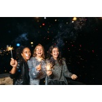 Three happy women having fun with sparklers. Outdoor party.