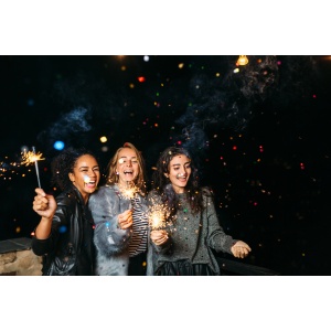 Three happy women having fun with sparklers. Outdoor party.