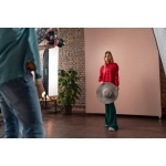 Young photographer taking picures of model, backstage of photoshooting in studio.