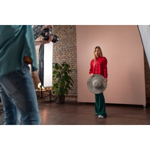 Young photographer taking picures of model, backstage of photoshooting in studio.